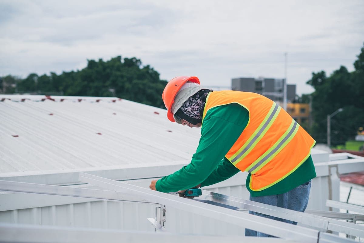 Worker in safety gear carrying out an installation on a rooftop