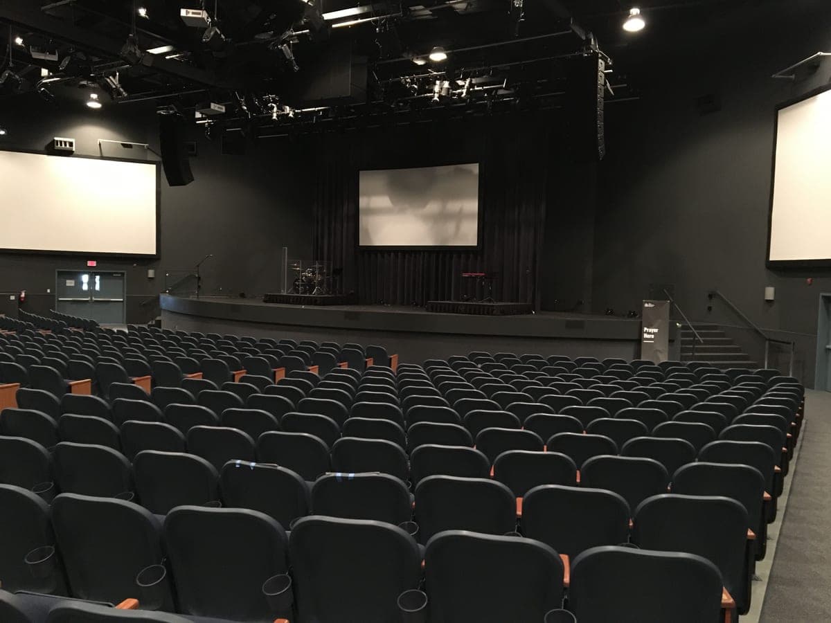 Rows of seats facing a stage with screens in a modern auditorium