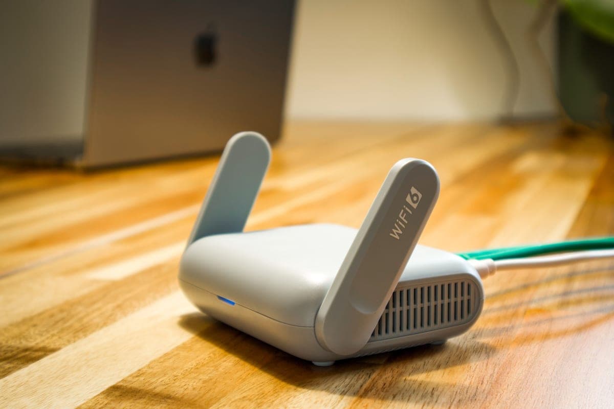 Wi-Fi router with antennas and a network cable on a wooden desk