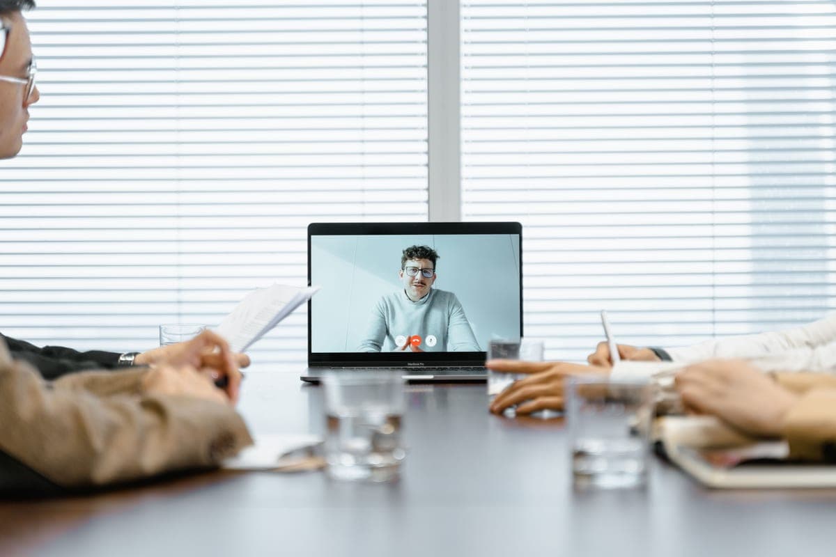 People taking part in a video meeting shown on a screen in an office